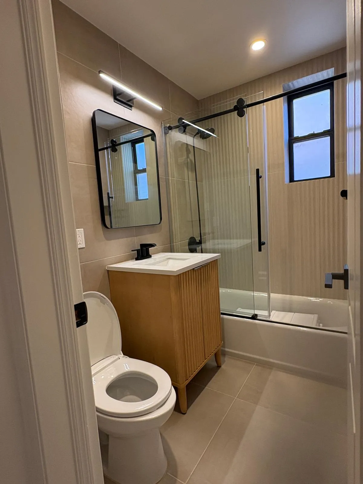 Great Neck bathroom with wood vanity, glass shower door, and black fixtures