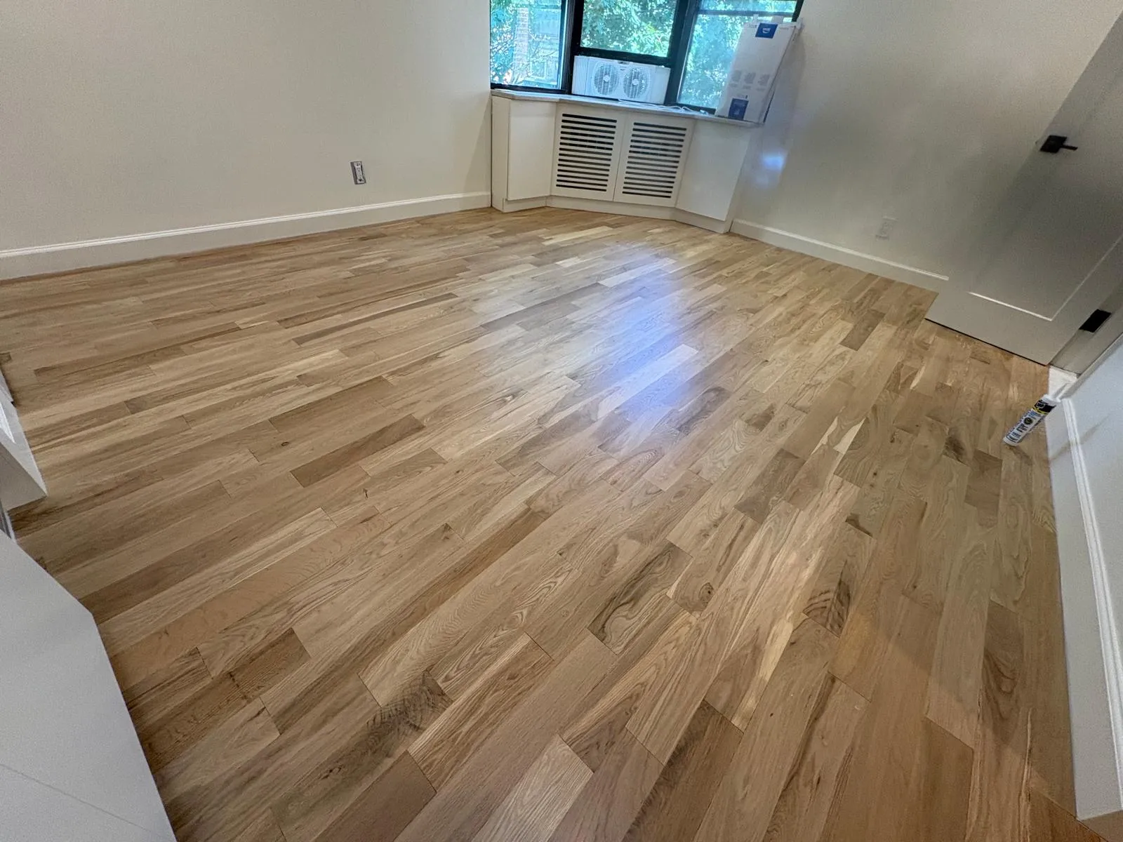 Refinished hardwood floor in a bright Great Neck bedroom renovation