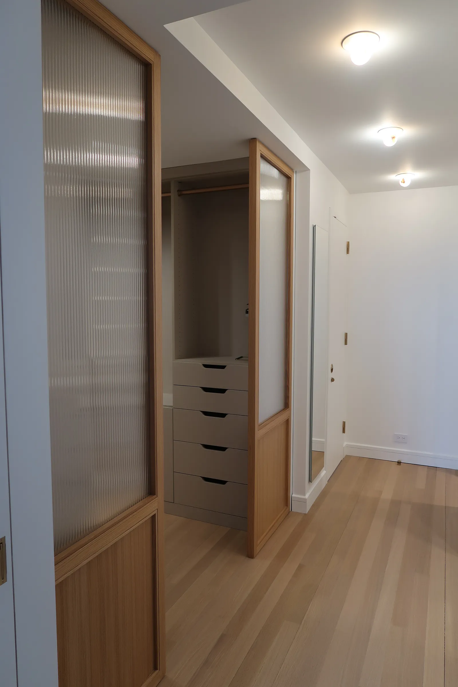 Wood and ribbed-glass room divider with integrated storage at the Lafayette Residence