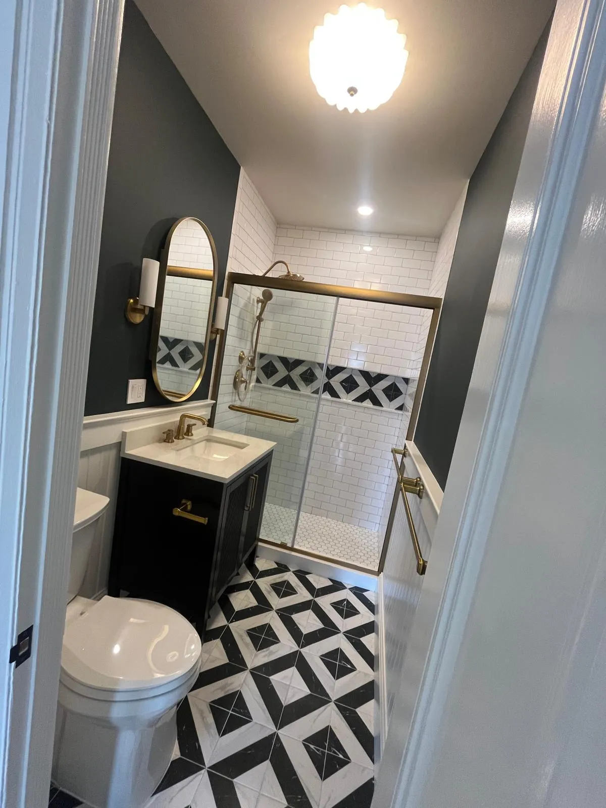 Park Slope bathroom with brass fixtures, dark walls, and patterned tile floor