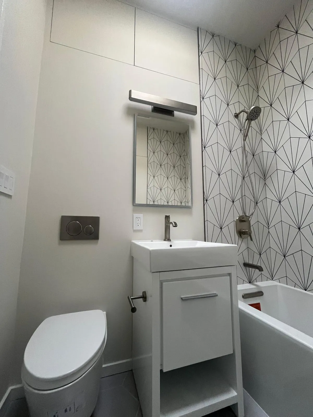 Compact white vanity and geometric wall tile in a Park Slope bathroom renovation