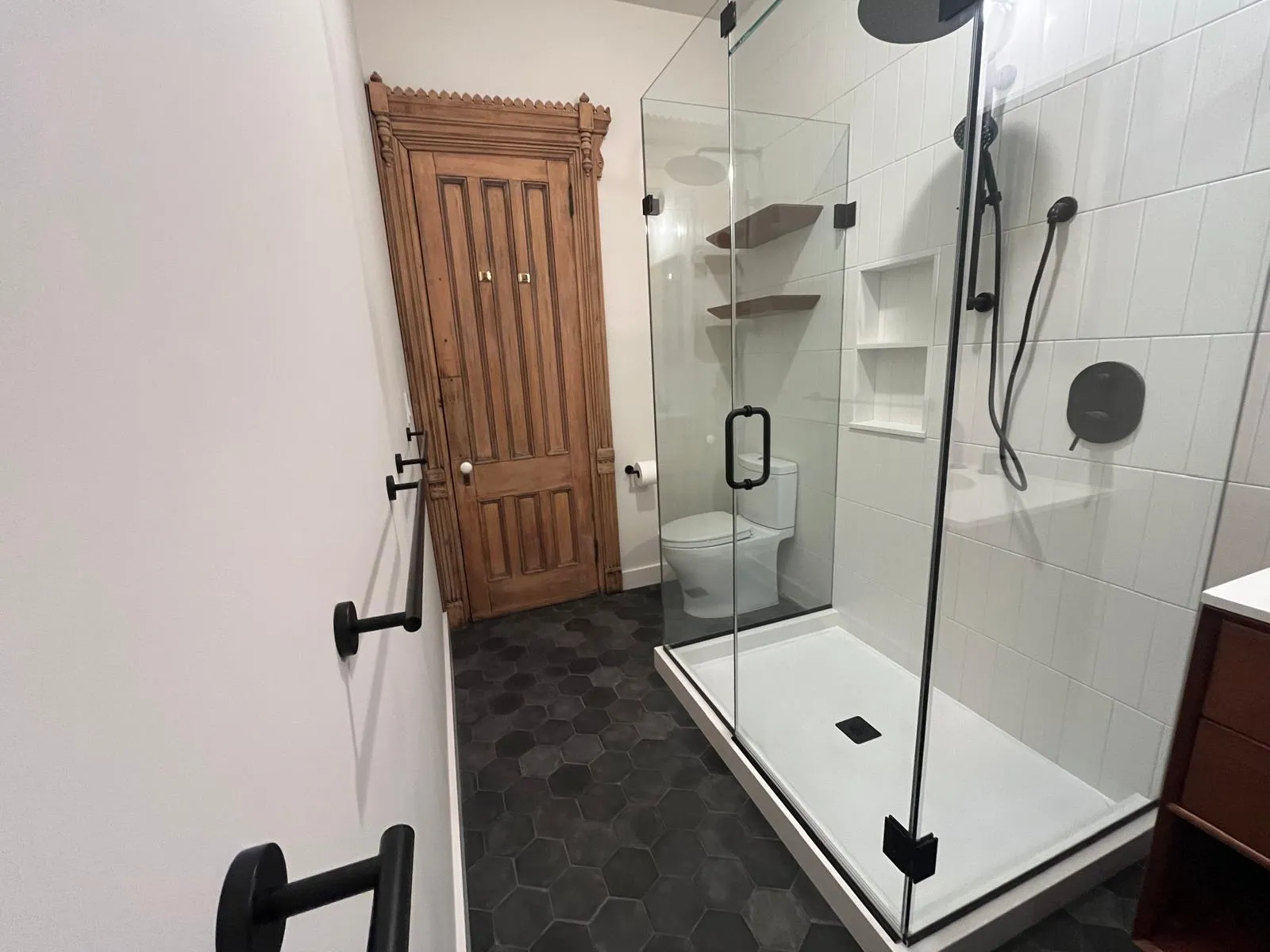 Glass shower enclosure and restored woodwork in a Park Slope bathroom renovation